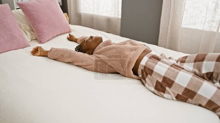 Foto de Mujer afroamericana con trenzas relajándose en el dormitorio en casa, retratando la comodidad y la tranquilidad. - Imagen libre de derechos