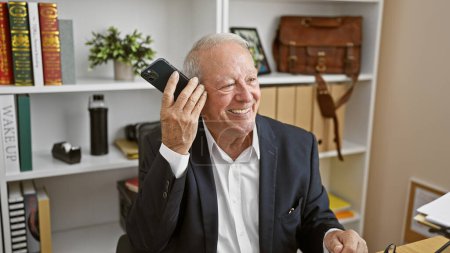 Téléchargez les photos : Senior homme d'affaires à l'écoute des messages vocaux par smartphone travaillant au bureau - en image libre de droit