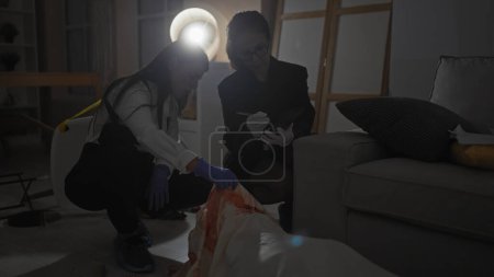 Téléchargez les photos : Deux femmes enquêtrices analysent des preuves sur une scène de crime à l'intérieur la nuit, l'une prenant des notes. - en image libre de droit