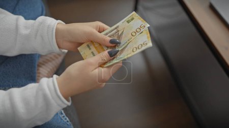 Photo for Caucasian woman counting norwegian currency indoors, depicting finance, home budgeting and economy. - Royalty Free Image