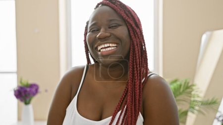 Portrait of a smiling african american woman with braids in a bright indoor home setting
