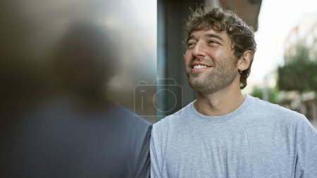 Photo for Cheerful young man, confidently looking side with a winning smile, enjoying city's street life. - Royalty Free Image