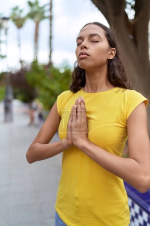 Photo for Young african american woman praying with closed eyes at park - Royalty Free Image