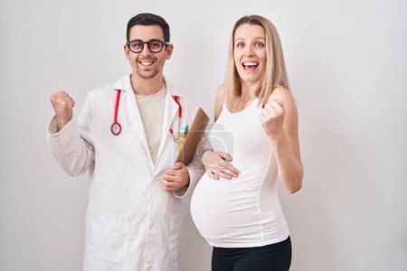 Téléchargez les photos : Jeune femme attendant un bébé avec un médecin criant fier, célébrant la victoire et le succès très excité avec le bras levé - en image libre de droit