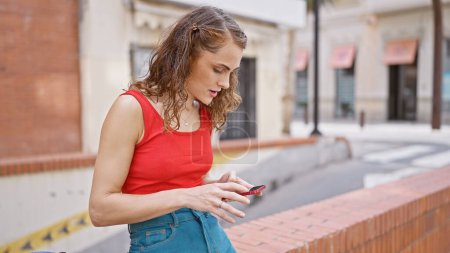 Photo for Cool lifestyle, young woman seriously concentrated on texting message with smartphone on a sunny town street - Royalty Free Image