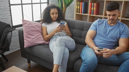 Un hombre y una mujer se involucran con sus teléfonos inteligentes en una acogedora sala de estar del apartamento, lo que demuestra un estilo de vida interior moderno.