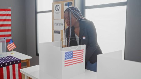 Mujer afroamericana con trenzas votando en un colegio electoral, adornado con banderas.