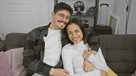 A smiling couple cuddles on a sofa in a cozy living room, evoking a sense of love, home, and togetherness.