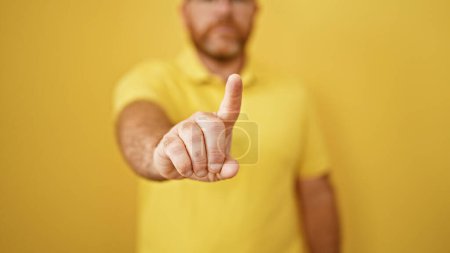 Hombre caucásico diciendo no con el dedo sobre el fondo amarillo aislado