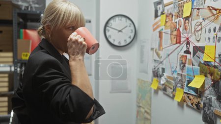 Téléchargez les photos : Une femme blonde enquête sur un crime au poste de police, examinant un tableau d'indices tout en sirotant un café. - en image libre de droit