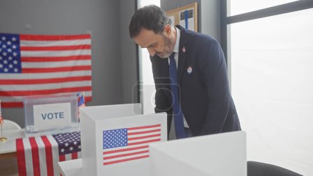 Foto de Hombre barbudo maduro votando en sala electoral americana con banderas - Imagen libre de derechos