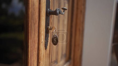Téléchargez les photos : Gros plan d'une vieille clé dans la serrure d'une porte en bois, marquée avec le numéro 5, évoquant une atmosphère rustique et sécurisée. - en image libre de droit
