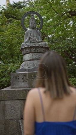 Foto de Hermosa mujer hispana en gafas encuentra paz rezando a Buda en el antiguo templo senso-ji de Tokyo - Imagen libre de derechos