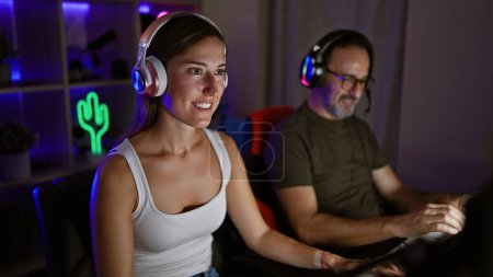 Foto de Padre e hija juntos en la gloria de los juegos, dos jugadores sonrientes se deleitan en la victoria de los videojuegos en la sala de juegos en casa - Imagen libre de derechos