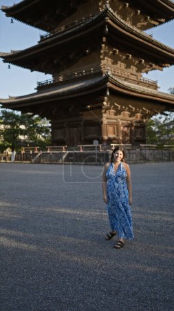 Beautiful hispanic woman standing, smiling confidently in front of japan's to-ji temple, radiating happiness and carefree joy, her friendly expressiveness making this kyoto park even more enjoyable.