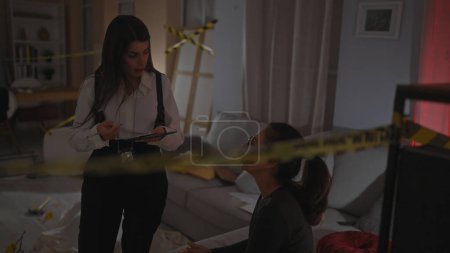Policewoman interrogates woman indoors with caution tape, notebook, evidence, crime scene, mystery, discussion, female, investigation, officer, serious.