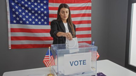Una joven hispana vota adentro con una bandera americana detrás de ella, simbolizando la participación democrática.