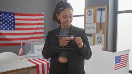 Foto de Pins de mujer hispana 'voté' pegatina en el interior en nosotros colegio electoral con bandera americana - Imagen libre de derechos