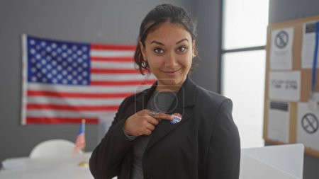 Foto de Joven mujer hispana señalando a la etiqueta 'yo voté' dentro con el telón de fondo de la bandera americana, evocando el deber cívico y el orgullo. - Imagen libre de derechos
