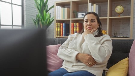 Photo for Mature hispanic woman contemplating in a cozy living room, evoking a serene ambiance. - Royalty Free Image