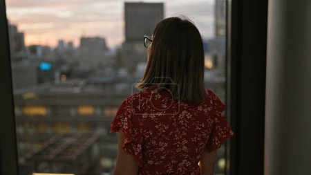 Hermosa mujer de negocios hispana en gafas, cautivadora vista del paisaje urbano desde la ventana del rascacielos en el horizonte urbano de Japón