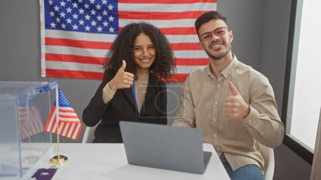 Lächelnde Männer und Frauen geben in einem Wahlzentrum der Vereinigten Staaten mit Flagge und Laptop die Daumen hoch.