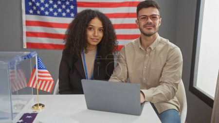 Un hombre y una mujer se sientan en un interior con una bandera de EE.UU., simbolizando un contexto electoral político.