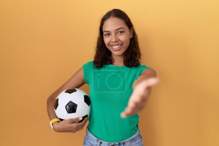 Téléchargez les photos : Jeune femme hispanique tenant le ballon souriant joyeuse offrant la main de la paume donnant assistance et acceptation. - en image libre de droit
