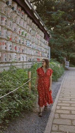 Photo for Beautiful hispanic woman smiling, standing by shake barrels at meiji temple while embracing japanese culture, all while donning glasses - Royalty Free Image