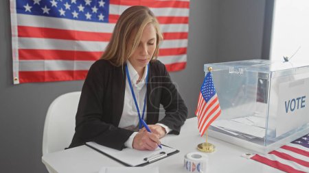 A young woman in business attire is focused on writing in an american polling station with flags and a ballot box.
