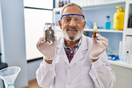 Hombre mayor alegre, mostrando sus dientes perfectos con una sonrisa fresca, exhibe orgullosamente la medicina del cannabis en el laboratorio, irradiando pura alegría y confianza