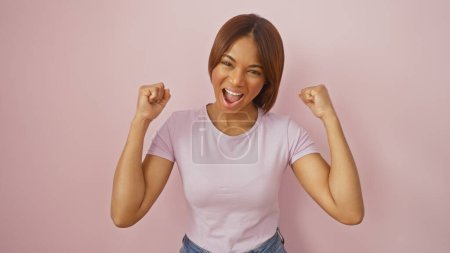 Excited african american woman clenched fists pink background