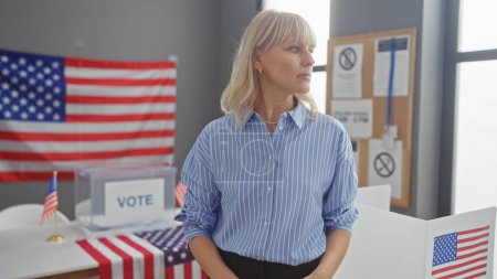 Foto de Mujer rubia pensativa en un centro electoral universitario con bandera americana y cabina de votación. - Imagen libre de derechos