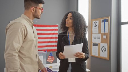 Man and woman converse in a usa electoral center with an american flag and voting signage