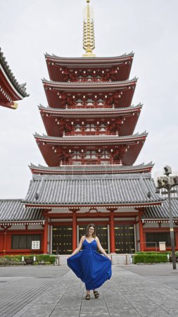 Effervescent hispanic woman dances joyfully, spinning in beautiful dress amidst senso-ji temple's splendid architecture in tokyo. touring japan, she exudes happiness in urban vacation adventure.