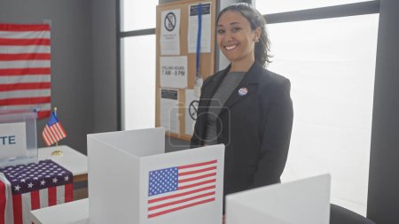 Smiling young woman with i voted sticker in a college electoral center, adorned with a us flag.