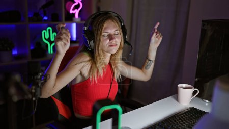 Foto de Una joven disfruta jugando de noche en su habitación iluminada por neón, mostrando tecnología y estilo de vida. - Imagen libre de derechos