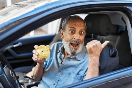 Photo for Cheerful elder man with white hair holds piggy bank near car, flashing a victory sign and beaming smile, happiness galore! - Royalty Free Image