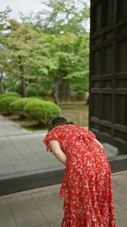 Gorgeous hispanic woman in glasses, bowing in prayer at tokyo's historical gotokuji temple, embracing buddhist traditions and japanese culture