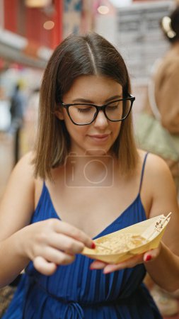 Chic hispanic woman devours traditional warabimochi dessert on bustling japanese street