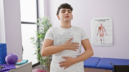 Young adult man practicing breathing exercises in a rehab clinic's therapy room.