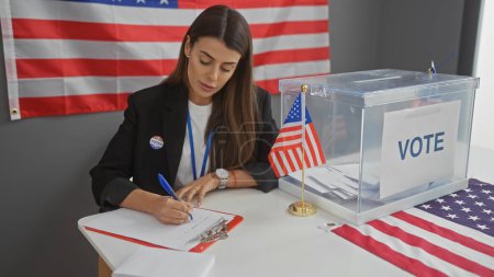 Una joven hispana en una chaqueta tomando notas en un colegio electoral americano con una bandera