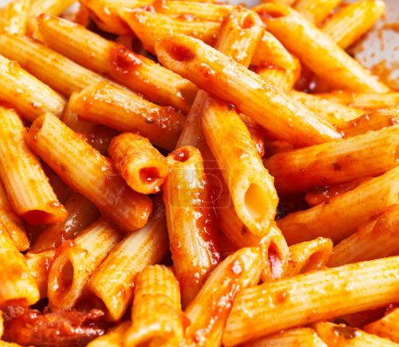 Photo for Close-up of delicious penne pasta coated in tomato sauce on a plate, implying italian cuisine. - Royalty Free Image