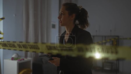 Une femme détective concentrée examine une scène de crime à l'intérieur, insigne évident, derrière la bande de prudence.