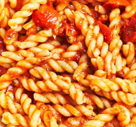 Foto de Primer plano de deliciosa salsa de tomate recubierta de pasta fusilli, ideal para diseños temáticos de cocina italiana. - Imagen libre de derechos