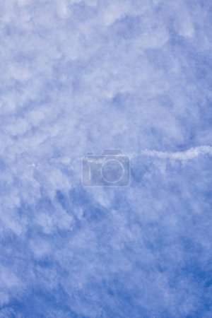 Téléchargez les photos : Vaste ciel bleu avec des nuages doux et texturés et un sentier aérien singulier traversant l'étendue sereine. - en image libre de droit