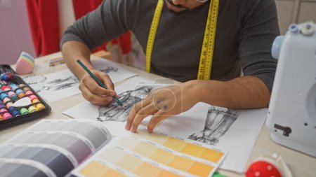 Téléchargez les photos : Un homme concentré taillant dans un atelier bien équipé, entouré d'articles à coudre et de palettes de couleurs. - en image libre de droit
