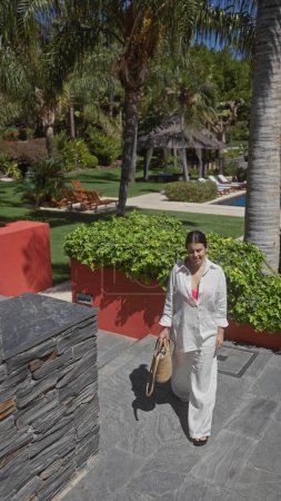 Téléchargez les photos : Une jeune femme hispanique profite d'une journée ensoleillée dans un complexe bali haut de gamme, rayonnant de beauté dans un cadre extérieur. - en image libre de droit