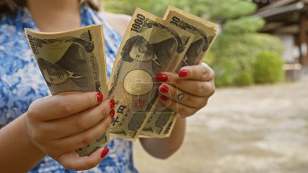 Foto de Las manos de una joven caucásica cuentan la riqueza de los billetes de yen de Japón en el jingu heian tradicional, kyoto, un símbolo de la riqueza financiera asiática - Imagen libre de derechos