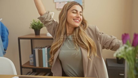Femme joyeuse s'étirant dans un bureau moderne pendant une pause, évoquant le bonheur et un environnement de travail détendu.